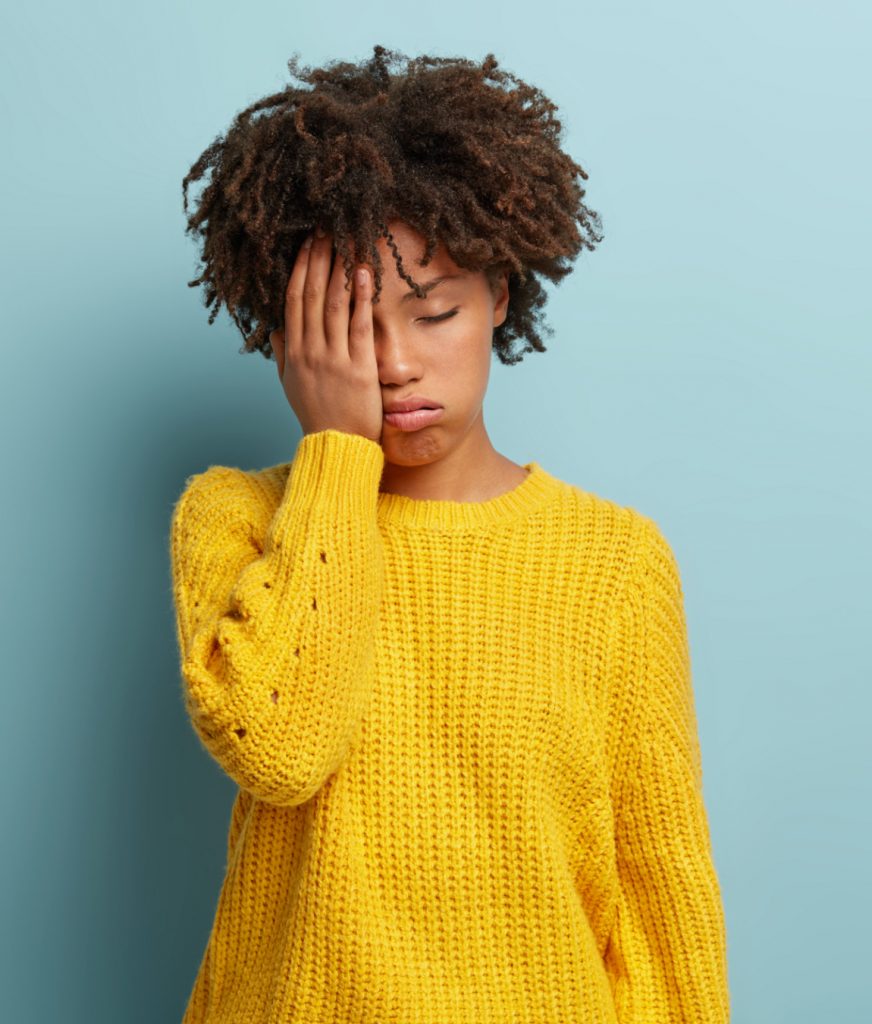 Woman in yellow sweater experiencing fatigue